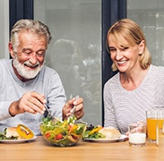 a mature man eating with dental implants in Estero