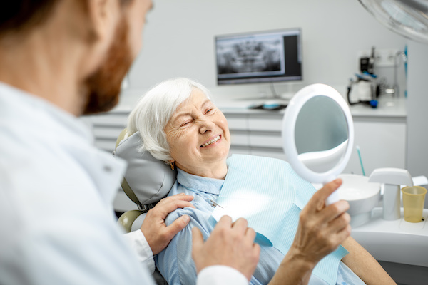 older woman smiling at reflection in the dentist's office
